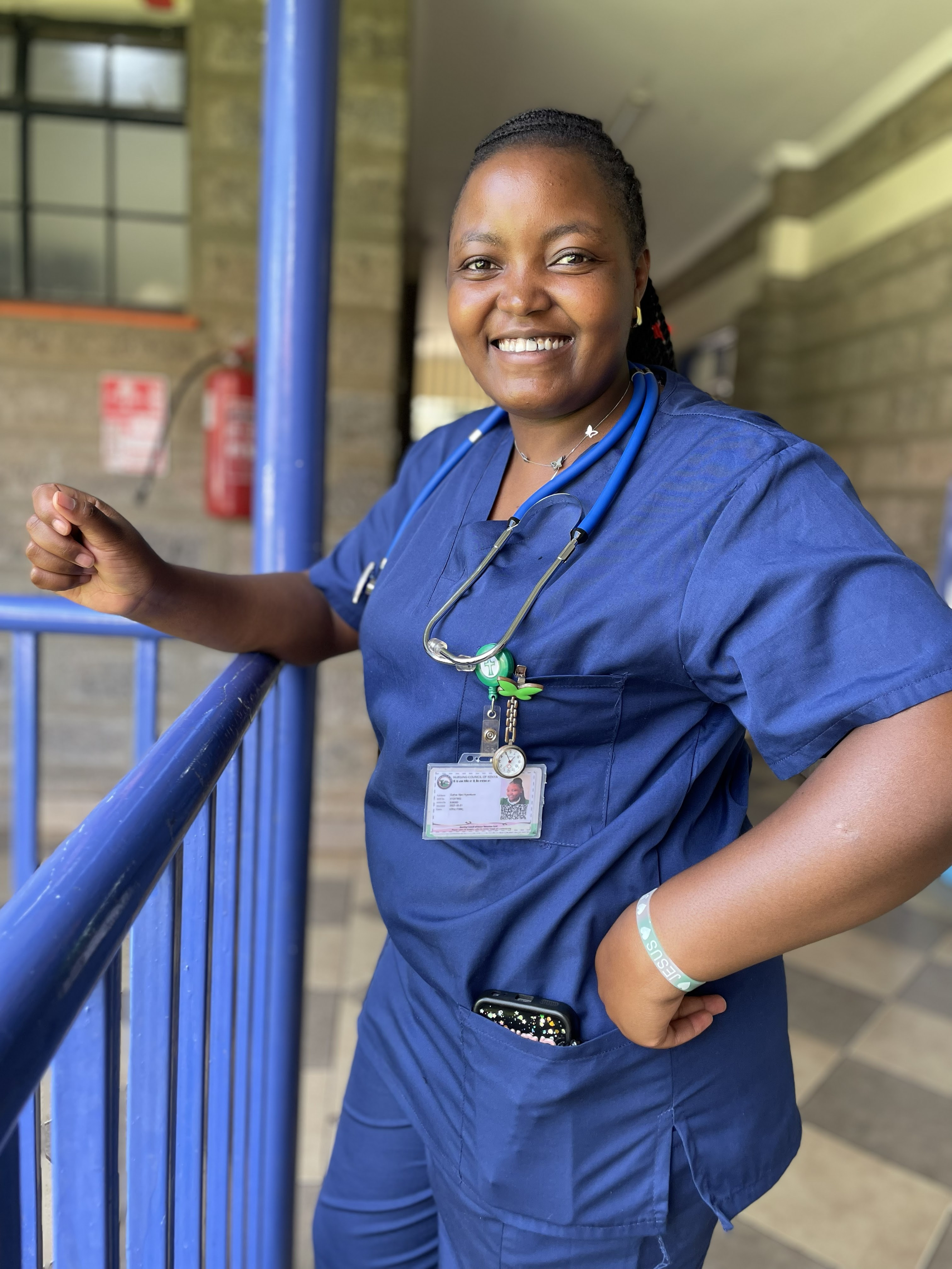 Esther, a registered nurse, smiling in her blue scrubs